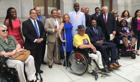 A group photo. There are 6 people with apparent disabilities, 4 people are using wheelchairs, 1 person is using crutches & another is holding a white cane.