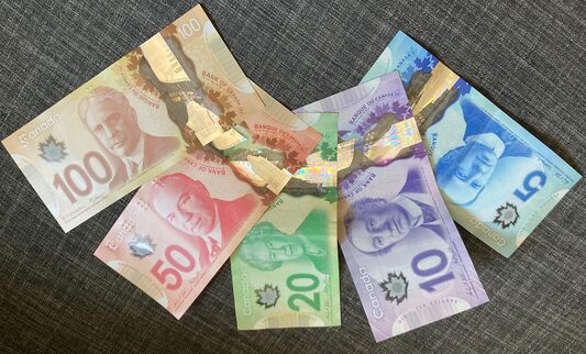 Canadian paper currency from left to right $100, $50, $20, $10, $5